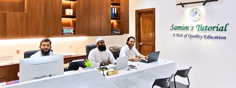 Three staff members at the front desk, with the Samim's Tutorial sign on the wall